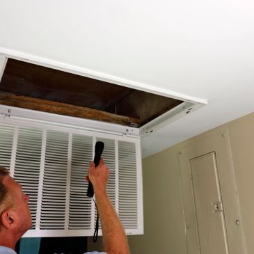 Person inspecting ceiling vent with a flashlight.