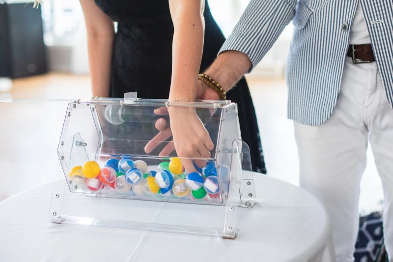 Process of prize drawings, extracting a winning numbers of lottery machine, raffle drum with a bingo balls and winning tickets on event with a host and hands on lottery machine"n