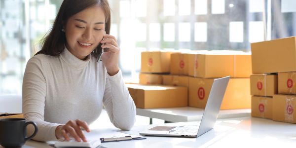 Woman talking on phone while working with packages.