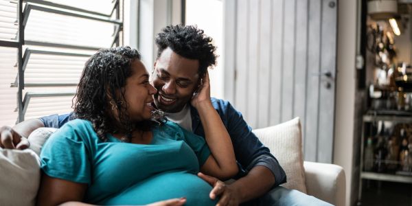 A loving couple shares a joyful moment at home, expecting a baby.
