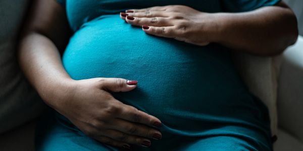 A pregnant woman holds her stomach.
