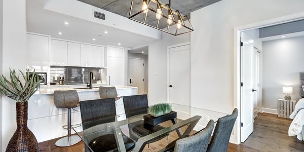Modern dining and kitchen area with glass table and bar stools.