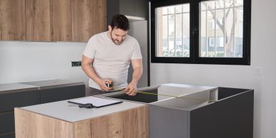 Man measuring kitchen countertop with tape measure.
