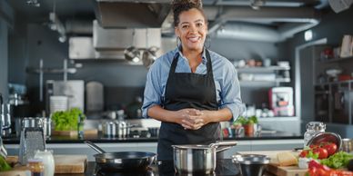 Smiling chef in apron preparing food in a modern kitchen.