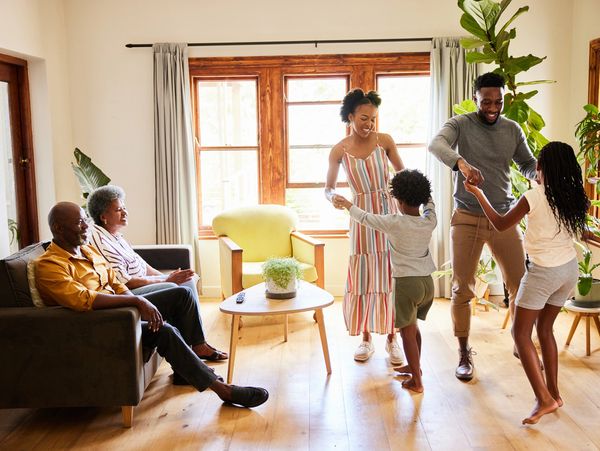 A joyful family moment while 
parents dancing with their children as grandparents look on with love.