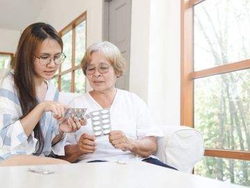 A woman helping a senior sort through her medications.