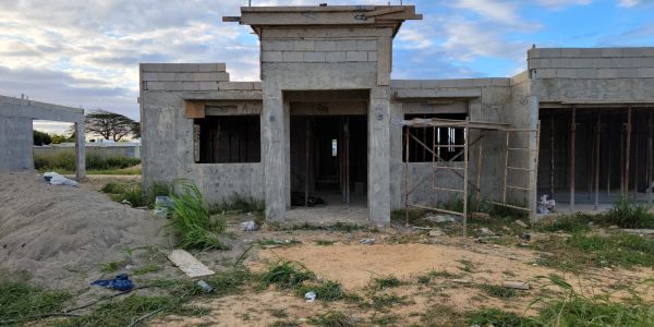 Unfinished cement building under cloudy sky.