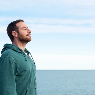 Man on the beach feeling peaceful and relaxed following his hypnotherapy session.