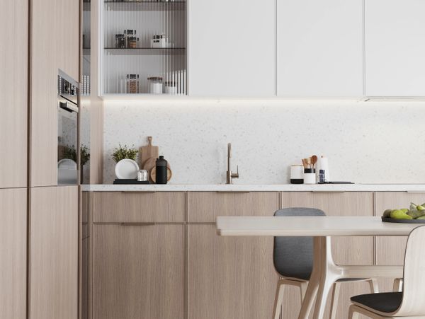 Modern kitchen with light wood cabinets and white countertops.