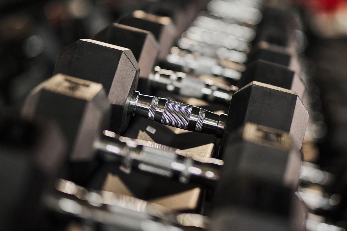 Rows of hexagonal dumbbells neatly arranged on a rack.