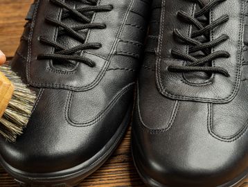 Close-up of black leather shoes being brushed with a shoe brush.