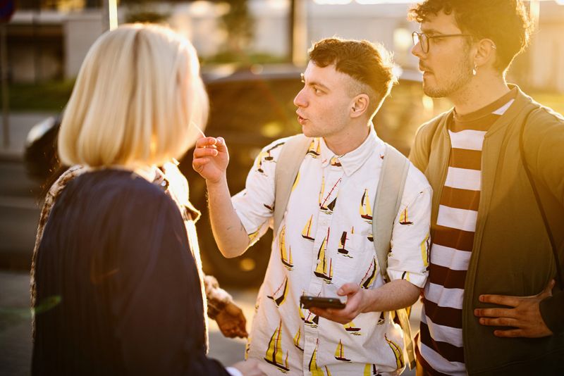 Group of friends lost in the city streets looking at maps on their smartphones
