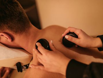 Person receiving hot stone massage on back.