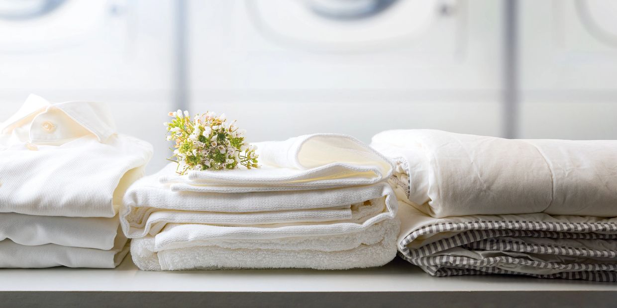 Neatly folded white laundry with a small flower on top.