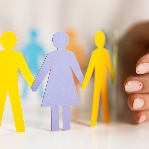 Hands protect a circle of colorful paper cutout people.