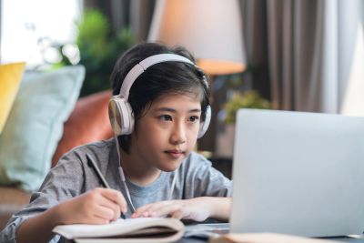 Boy studying with headphones and laptop.
