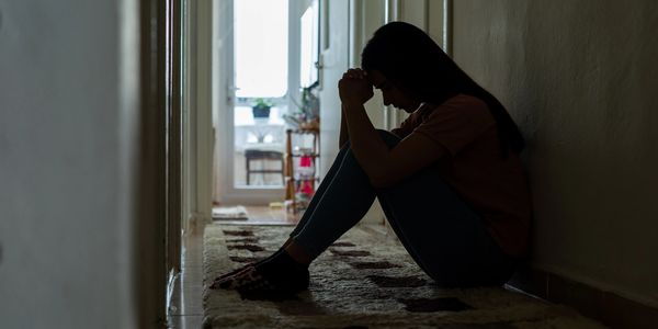 Silhouette of a person sitting in a hallway, appearing contemplative.