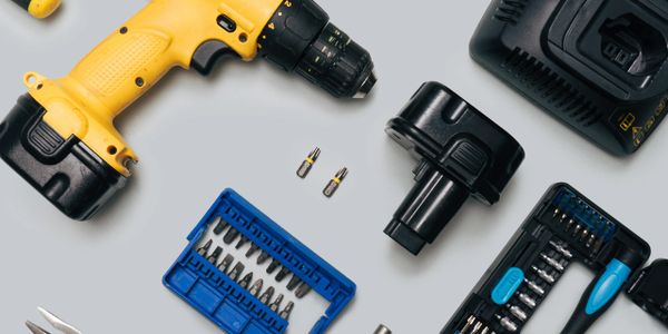 Cordless drill and assorted screwdriver bits neatly arranged on a gray surface.