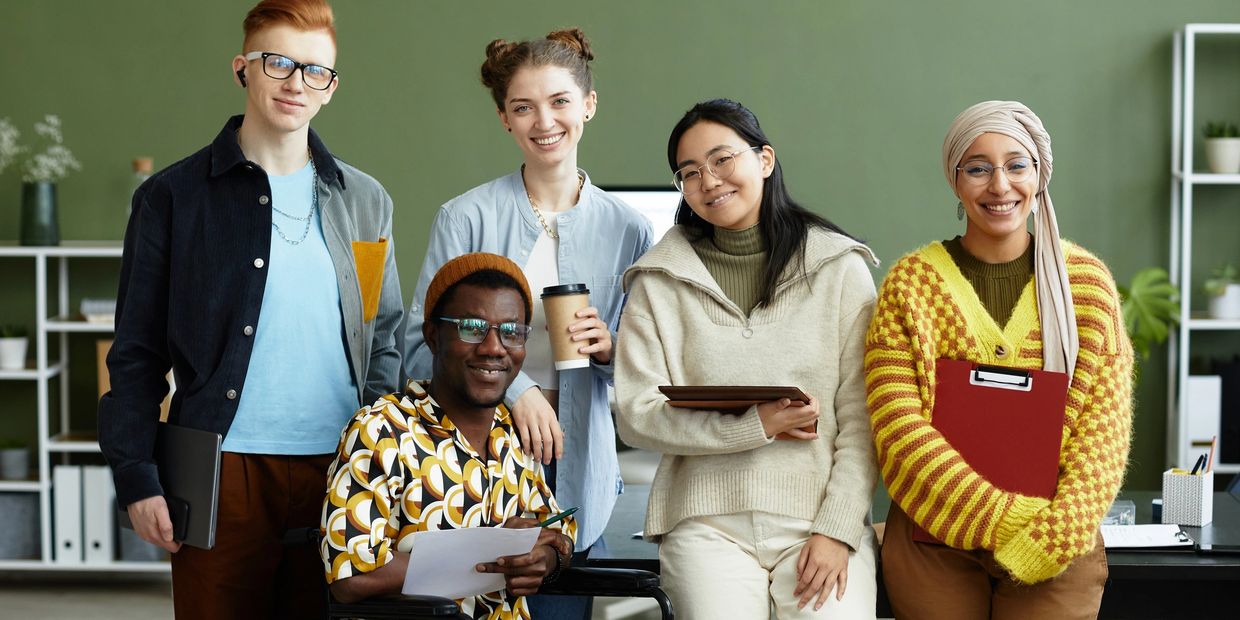 Group of five diverse young professionals smiling.