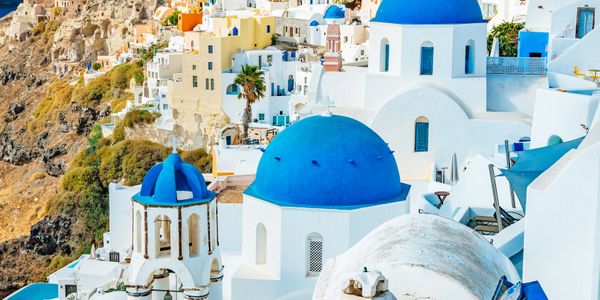 Blue-domed churches in a sunny Santorini village.