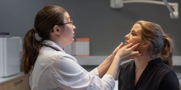 Doctor examining a woman's face in a medical office.