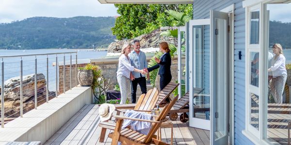 Couple meeting a real estate agent on a scenic waterfront deck.