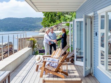 Three people greeting on a waterfront deck.