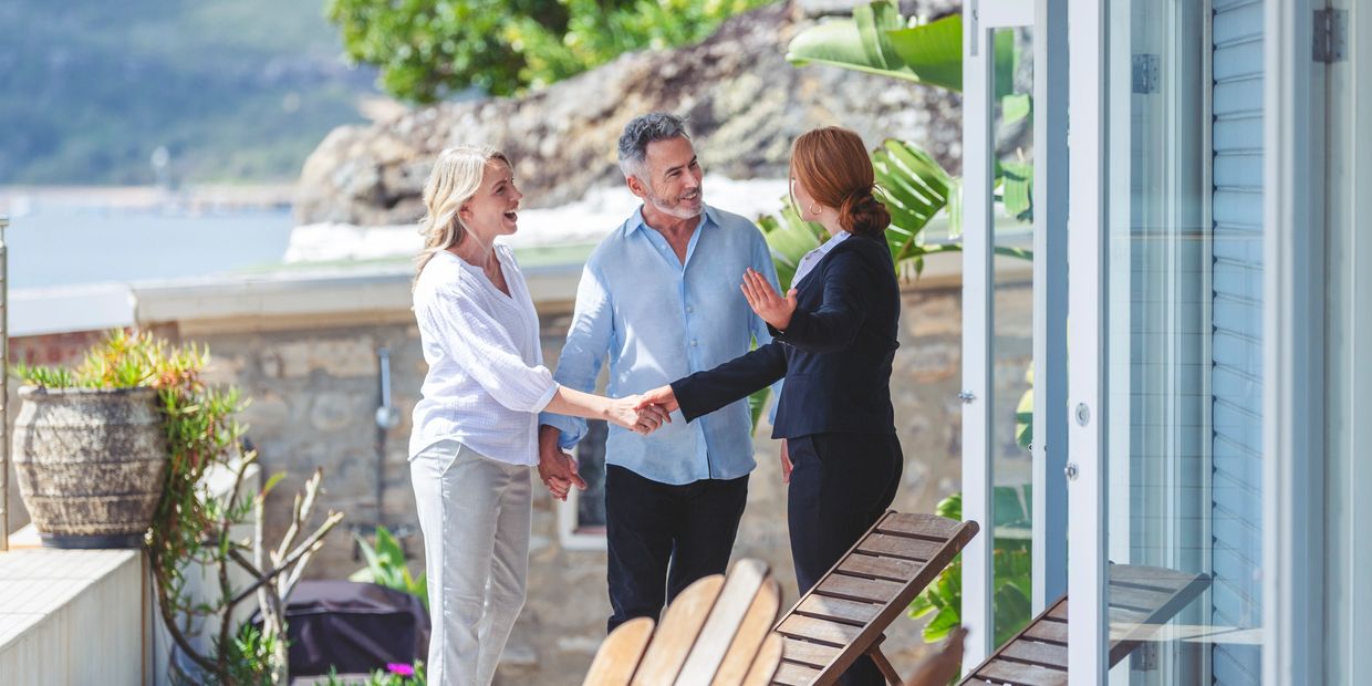 Couple greeting realtor on patio.