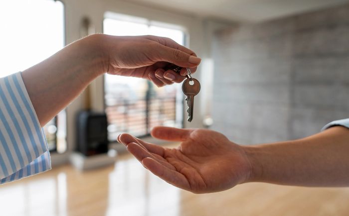 Handing over a key indoors, symbolizing trust or new beginnings.