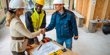 Professionals shaking hands at a construction site meeting.