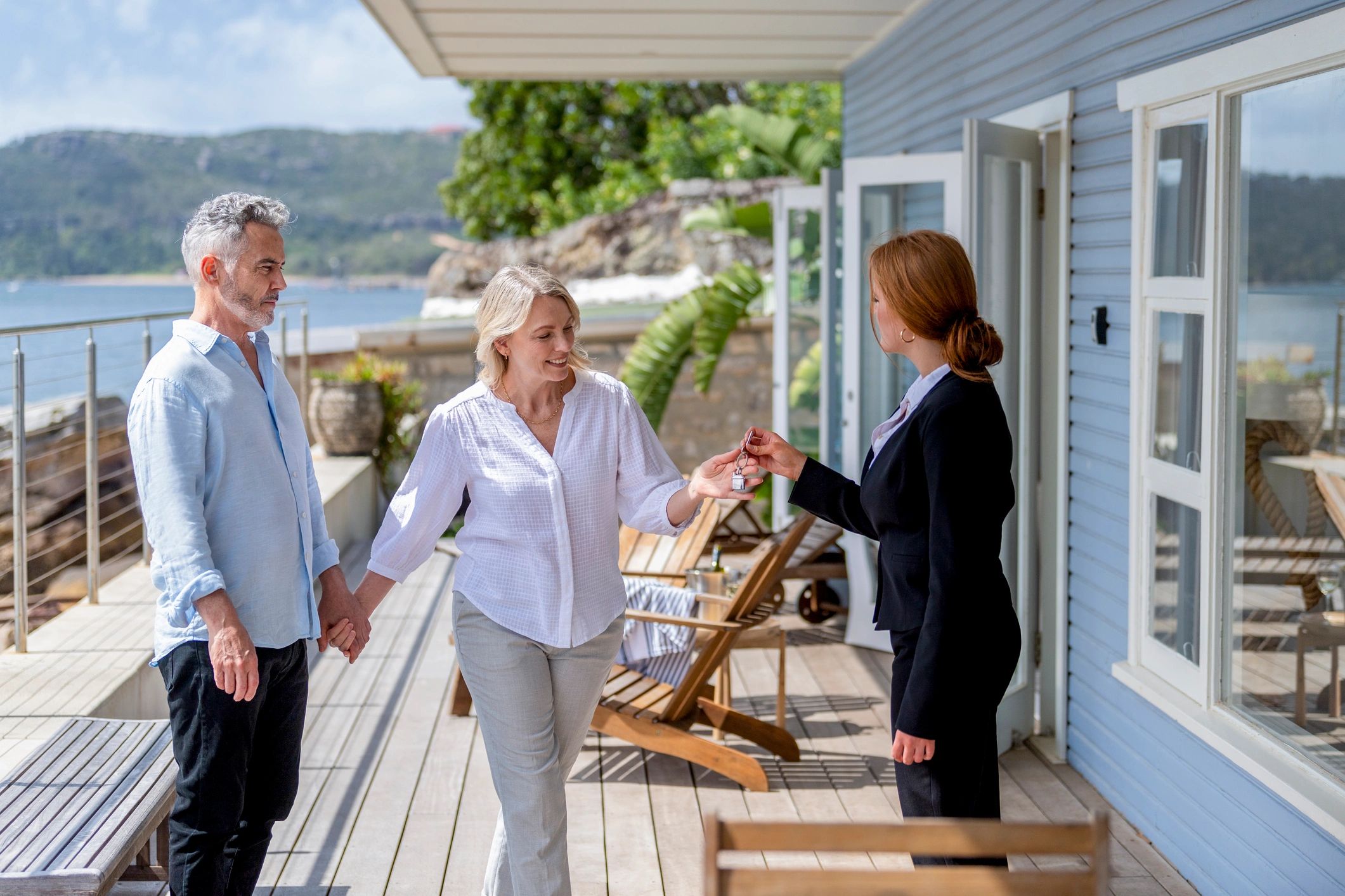 Real estate agent handing over house keys to a happy couple on a terrace.