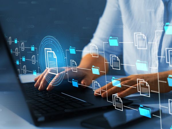 Person interacting with virtual digital file icons over a laptop keyboard.