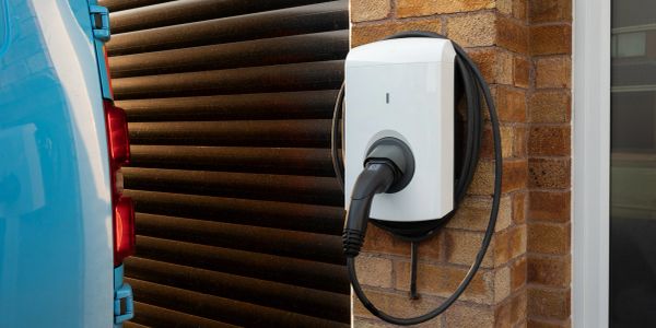 Electric vehicle charging station on a brick wall with a connected blue car.