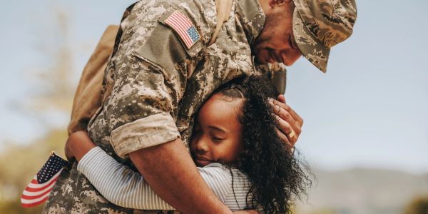 Military father hugging daughter after return.