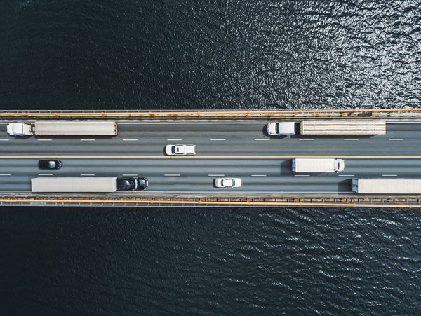 Aerial view of a busy bridge with trucks and cars over a body of water.