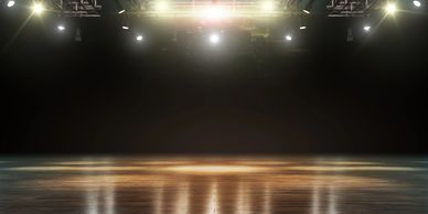 Stage illuminated with bright spotlights reflecting on a polished floor.