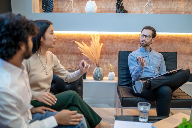 Experienced male psychotherapist listening to patients seated in his office during the family therapy session