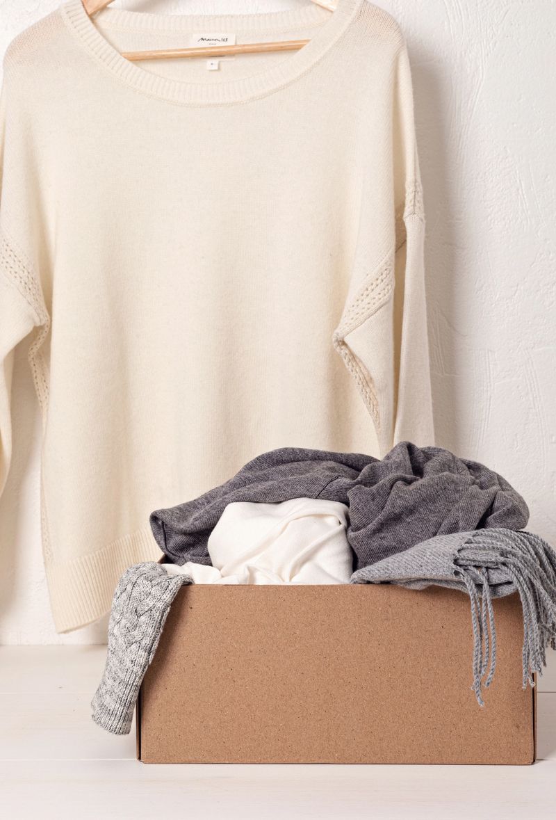 Pile of cozy knitted clothes for cold weather ready for donation. Comfort organic second hand sweaters. Thrift shop concept. Hygge style idea
