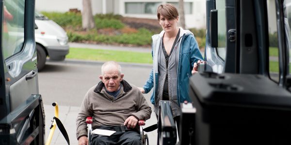 Wheelchair passenger receiving assistance while boarding a wheelchair-accessible transportation vehi