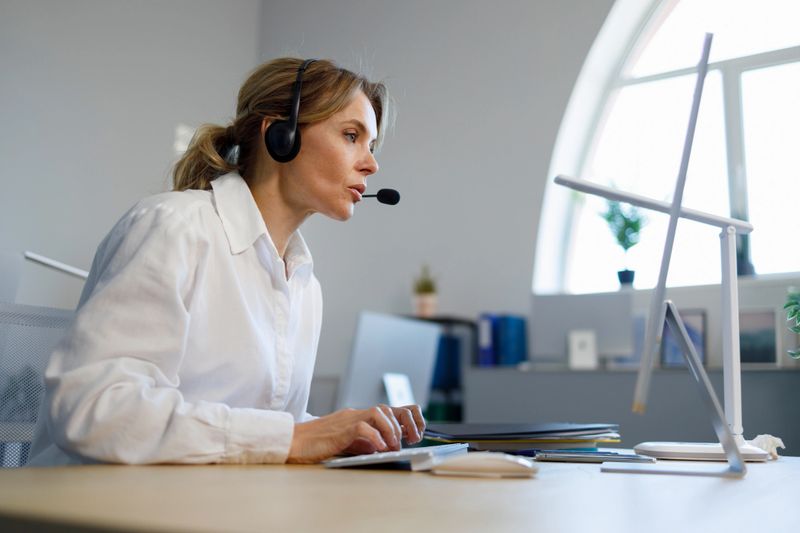 Business woman helpline operator in headset working at computer"n