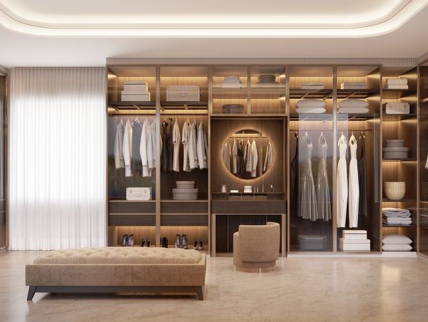 Luxurious walk-in closet with glass cabinets, soft lighting, and elegant beige seating.