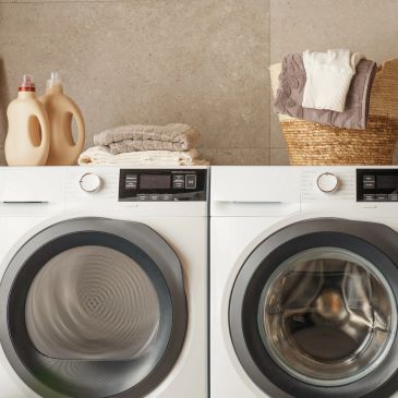 Two front-loading washing machines with laundry items on top.