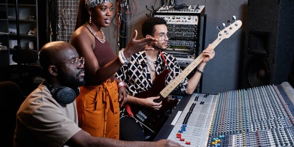 Three musicians collaborate in a recording studio.