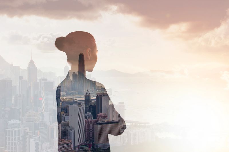 Young woman standing in contemplation in urban city reflection of Hong Kong, China