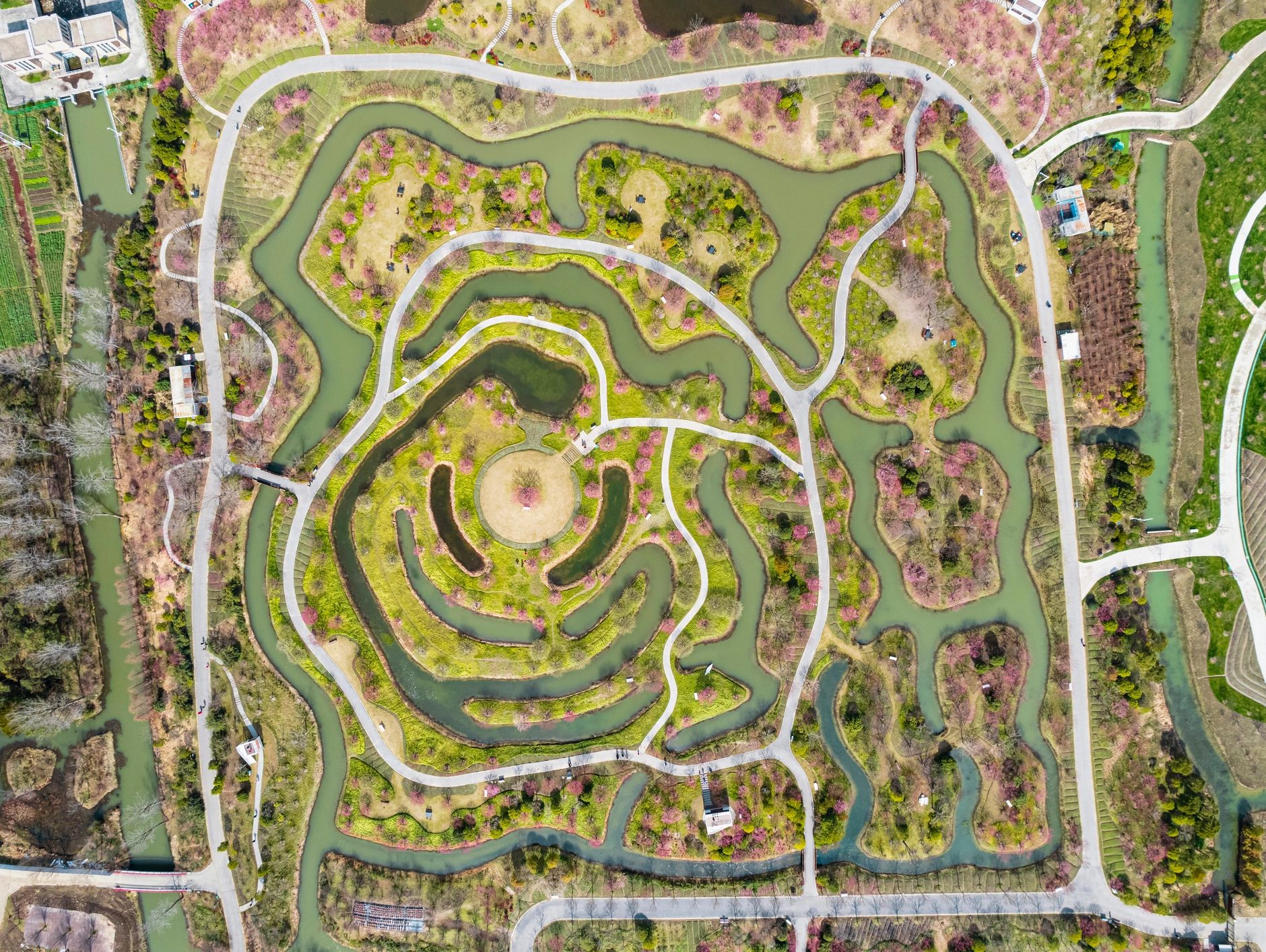 Aerial view of a park with winding paths and water channels forming a spiral.