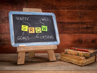 Chalkboard with the word GROW and motivational terms on a wooden table.