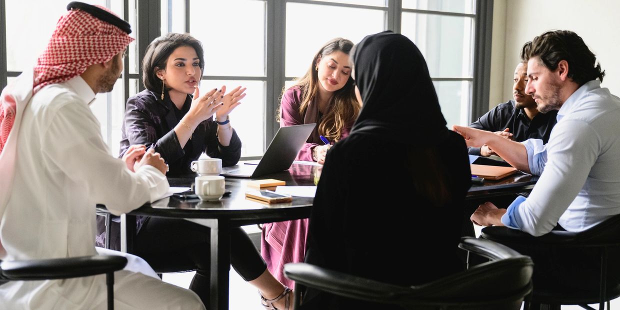 Diverse group having a serious business meeting around a table with laptops and coffee.