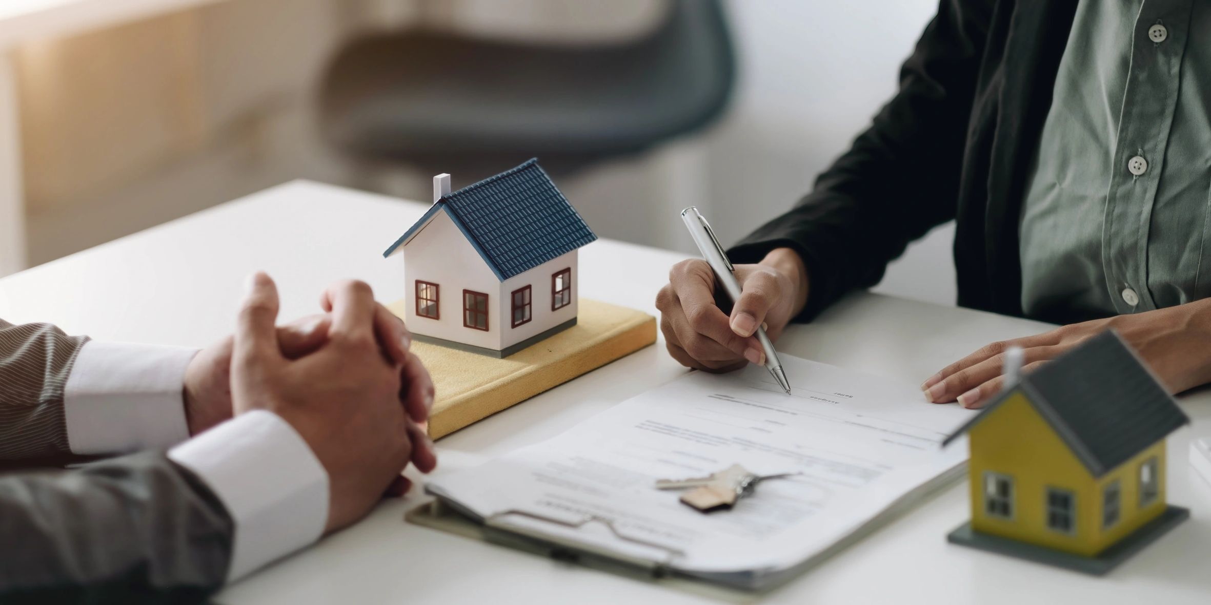 Homebuyers reviewing mortgage paperwork with model houses and keys