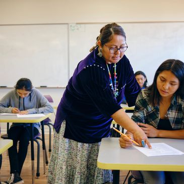 Teacher assisting student with exam in classroom.