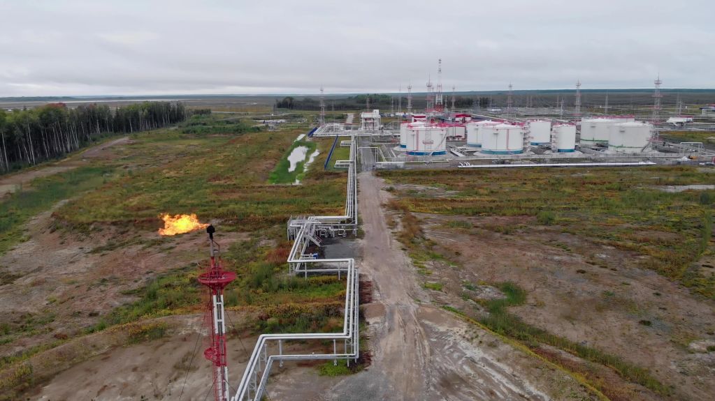 Industrial site with flame flare and storage tanks.